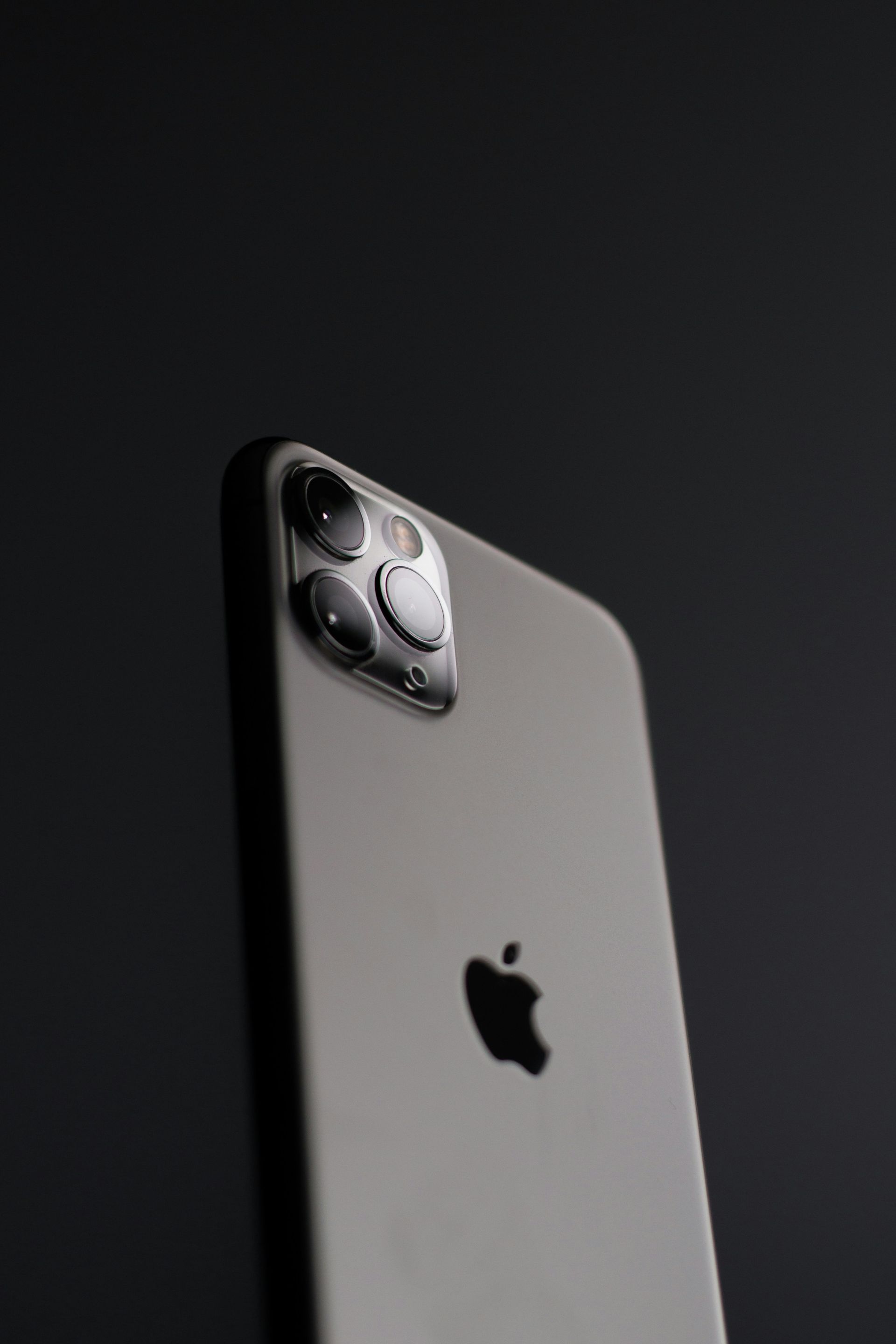 A grey smartphone with a triple camera array against a dark background